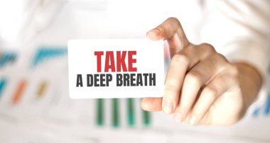 Bir iş kadını elinde bir kart tutuyor ve derin bir nefes alıyor.