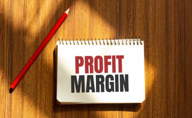 Beyaz arkaplanda metin PROFIT MARGIN içeren kırmızı kalem ve not defteri