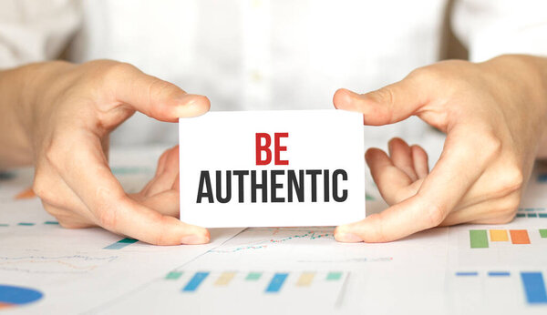 businesswoman holding a card with text BE AUTHENTIC