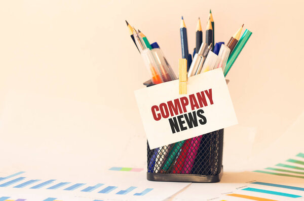 Card with text COMPANY NEWS on the pen box in the office. Diagram and white background