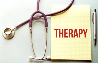 Mor arkaplanda, üzerinde THERAPY metni olan sarı listeli bir steteskop var.