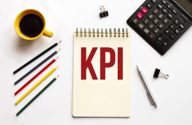 Kahve fincanı, hesap makinesi, not defteri, beyaz arka planda kalem ve kalemler. İş konsepti. KPI Metni