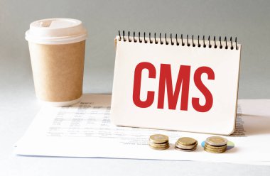 Kırmızı kalemle. Kahve fincanı. Kal. Klavye ve beyaz arka plan. Not defterinde CMS işareti