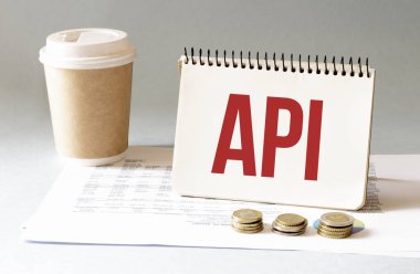 Kırmızı kalemle. Kahve fincanı. Kal. Klavye ve beyaz arka plan. Not defterinde API imzası