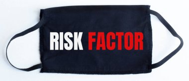 Siyah arkaplanda RISK FACTOR metni olan siyah tek kullanımlık koruyucu maske.