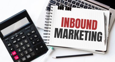 Dizüstü bilgisayar, hesap makinesi, kalem ve not defteri beyaz arkaplanda INBOUND MARKETING metni