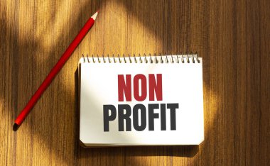 Beyaz arkaplanda NON PROFIT metni bulunan kırmızı kalem ve not defteri