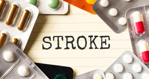 Beyaz arkaplanda STROKE mesajı. Yakınlarda çeşitli ilaçlar var. Tıbbi konsept