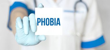 Doktor elinde PHOBIA yazılı kağıt tabak tutuyor, tıbbi konsept.