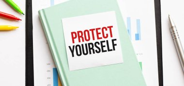 Beyaz büyük not defteri, yeşil kitap ve kâğıt sayfası üzerinde mali diyagram ve metin PROTECT kendin. İş konsepti