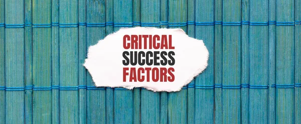 CRITICAL SUCCESS FACTORS text on the piece of paper on the green wood background