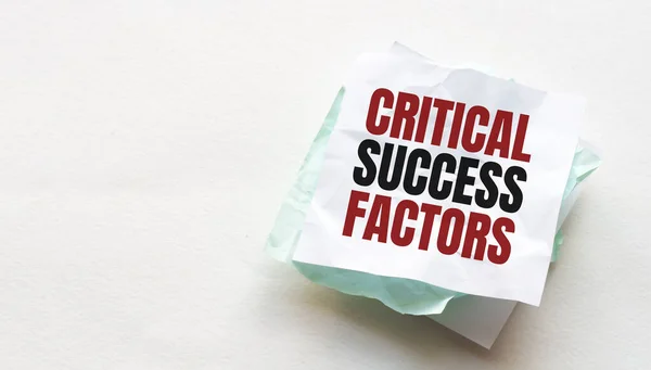 Tahta bir masaya defter ve kalem, metin için kopyalama alanı, buruşuk sarı kağıt, çalışma yeri, beyin fırtınası üzerine CRITICAL FACTORS yazan kadın el yazısı