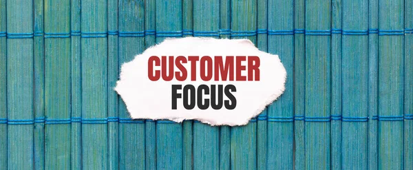 CUSTOMER FOCUS text on the piece of paper on the green wood background