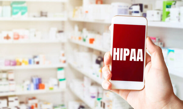 hand holding smart phone in pharmacy drugstore. Text HIPAA
