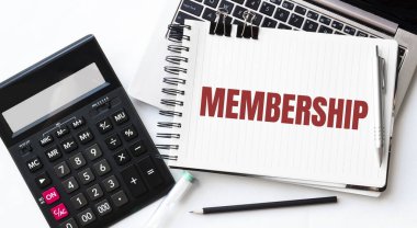 Dizüstü bilgisayarın klavyesi, hesap makinesi, kalem ve not defteri beyaz arkaplanda MEMBERship ile
