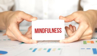 İş kadınının elinde içinde MINDFULNESS yazan bir kart var