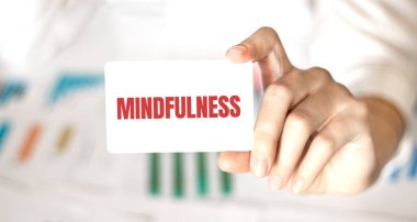 İş kadınının elinde içinde MINDFULNESS yazan bir kart var