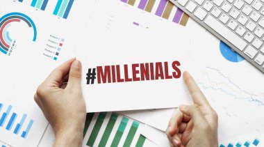 İş adamı elinde MILLENIALS yazılı bir kart tutuyor. Klavye, diyagram ve beyaz arkaplan