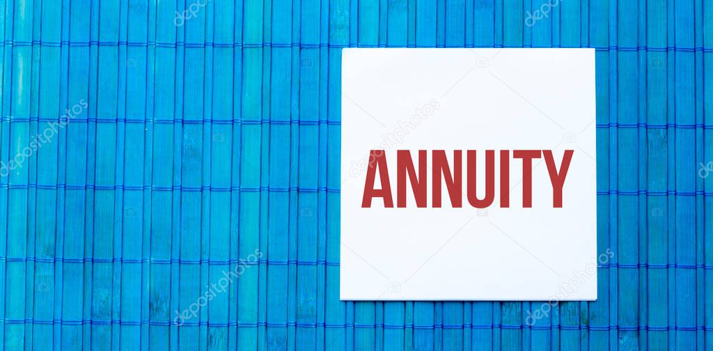 blank note pad with text ANNUITY on blue wooden background