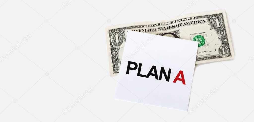 1 dollar bill and white notepad sheet on the white background. PLAN A text.