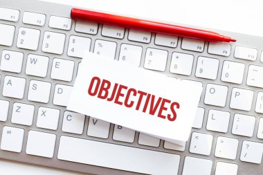 Bilgisayar klavyesindeki yırtık kağıda yazılmış OBJECTIVES sözleri