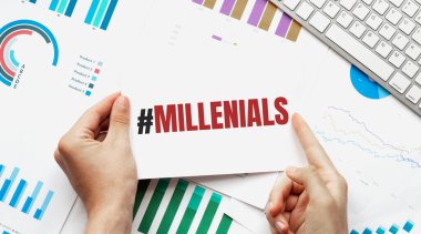 İş adamı elinde MILLENIALS yazılı bir kart tutuyor. Klavye, diyagram ve beyaz arkaplan