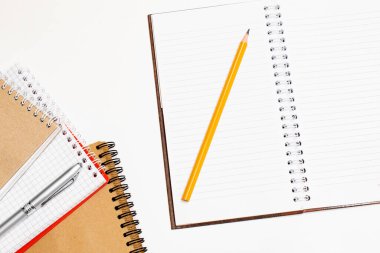 Beyaz masa arkasında kurşun kalemle kapalı siyah kapaklı defterin üst görünümü