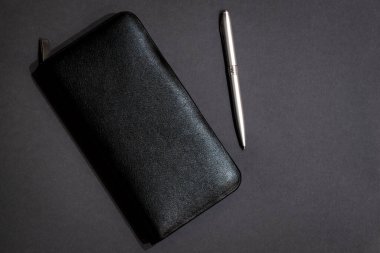 Masaüstündeki iş aksesuarları: defter, cüzdan, karanlık masadaki kalem. İş konsepti.