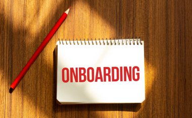 Beyaz arkaplanda ONBOARDING yazılı kırmızı kalem ve not defteri
