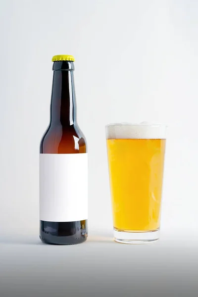 Beer Bottle Mock-Up with glass of lager and foam. Blank Label on white background