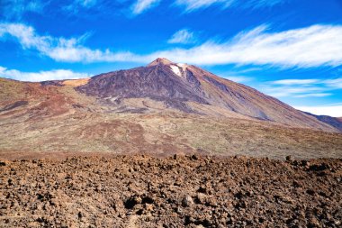 Jeolojik park vadisinden Teide volkanı (Tenerife) manzarası. Arkasında mor pigmentler ve mavi gökyüzü olan volkanik taş.. 