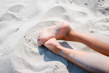 Tatil konsepti. Kadın ayakları sahilde dinleniyor, güneşin tadını çıkarıyor..