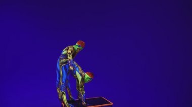 Neon kostümlü akrobatik ikizler kafalarında ve ellerinde, ultraviyole makyajlı mavi siklonamada bir duruş sergileyecekler. Parlak floresan vücut sanatı karanlıkta parlar..