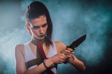 Beyaz elbiseli, siyah çoraplı, bıçaklı ve silahlı bir kız. Kıyametten sonraki biçim