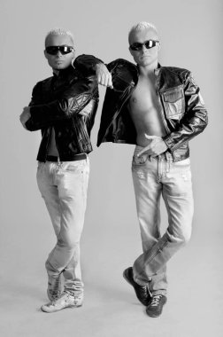 Deri ceketli ve beyaz arka planda kot giyen ikiz kardeşler.