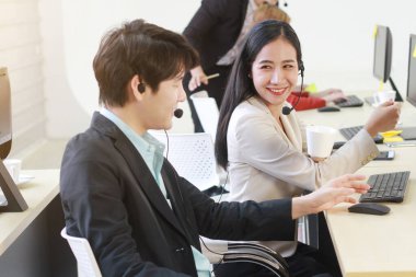 İş Çağrı Merkezi ve teknik destek personeli ya da resepsiyonist telefon operatörü bilgisayarla takım çalışmasını tartışıyor ve çalışıyor. Asyalı müşteri destek ekibi.