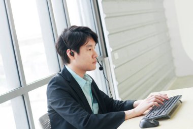 İş adamı çağrı merkezi ve teknik destek personeli kulaklıkla konuşuyor ve iş konusunda ciddi. Asyalı müşteri destek ekibi.