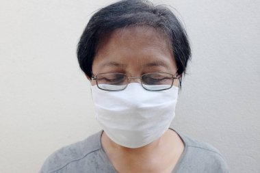 Tayland 'da Covid-19 veya Corona virüsünü önlemek ve Hava Kirliliği Değeri 2,5 Pm' yi korumak için gözlük ve beyaz bez maske takan Asyalı yaşlı kadın. Yaşlıların sağlık ve tıbbı