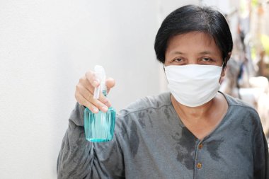 Beyaz maske takan Asyalı temizlikçi, Tayland 'da Covid-19 veya Corona virüsü ve Hava Kirliliği Değeri 2,5 ve avucuna dezenfekte etmek için alkol enjekte edilmesini engelliyor. Sağlık ve Hastalık Konsepti