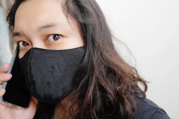 아시아인 코로나 바이러스 감염을 예방하기 천으로된 마스크를 착용하고 스마트폰으로 통화하고 — 스톡 사진