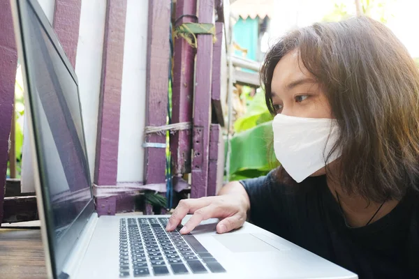 白い布のマスクをしたアジア系タイ人女性は 職場でノートパソコンのオンラインシステムで仕事をしているときに Covid 19やコロナウイルスのタイピングや会話を防ぐために着用しています 大気汚染値Pm — ストック写真