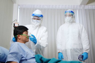 Kişisel Koruyucu Ekip ya da PPE giysileri ve Tayland 'daki hastanede tedavi gören Covid 19 virüsü bulaşmış Taylandlı yaşlı hasta için solunum cihazı kullanın.