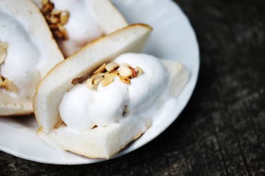 Tayland tatlısı. Beton zeminde beyaz tabağın üzerine fıstık ezmeli hindistan cevizli dondurma..