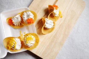 Tahta tabakta Tayland Çıtır Pankeki (Kanom Buang) ve beyaz arka planda izole edilmiş köpük kutusu