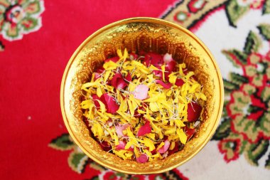 Red rose and Marigold flowers petals in gold tray in tradition Thai wedding ceremony and Buddhism in the temple clipart