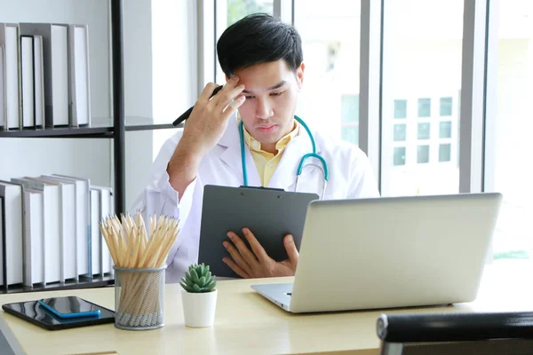 Ciddi Asyalı Psikiyatrist (MD) klinik depresyondaki akıl sağlığı sorunları için dizüstü bilgisayarla insan hayatını araştırıyor. Büyük depresif hastalar ve sağlık hizmetleri kavramı.