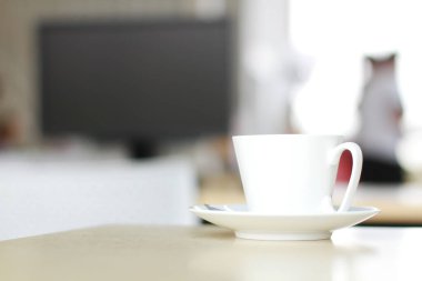 Beyaz seramik fincan sıcak kahve ya da ahşap bilgisayar masasında çay. Sabah ofisin ışıklarıyla birlikte. Kafein içecekleri taze bir hisse neden olur..