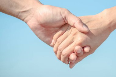 Çiftler mavi gökyüzü ve deniz arka planında el ele tutuşmayı severler. Sevgililer Günü ve Evlilik Konsepti 