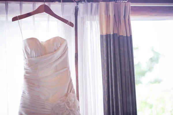 婚纱挂在窗帘栏杆上靠窗的房间里 — 图库照片