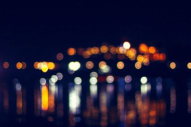 Bokeh 'in nehirde bulanıklaştığı güzel gece ışığı ve renkli suda refleks.